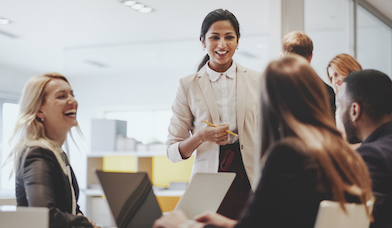 Group of professionals talking and laughing around the office