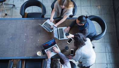 Team collaborating on laptops around conference room table