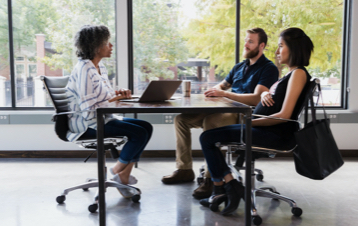 Three people sitting at a table with a laptop.