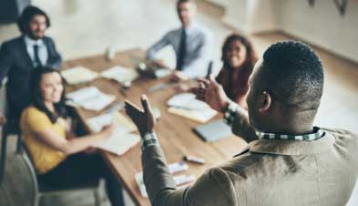 Man leading team in discussion around conference table