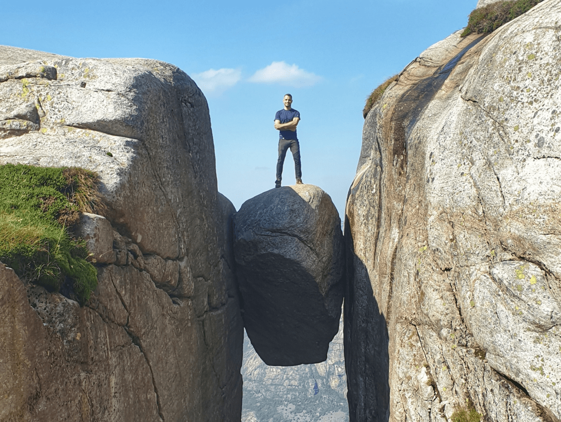 Person standing between two rock cliffs with arms folded, looking victorious.