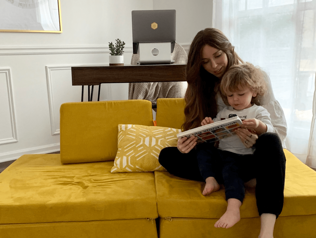 Person reading to a small child in their home office.